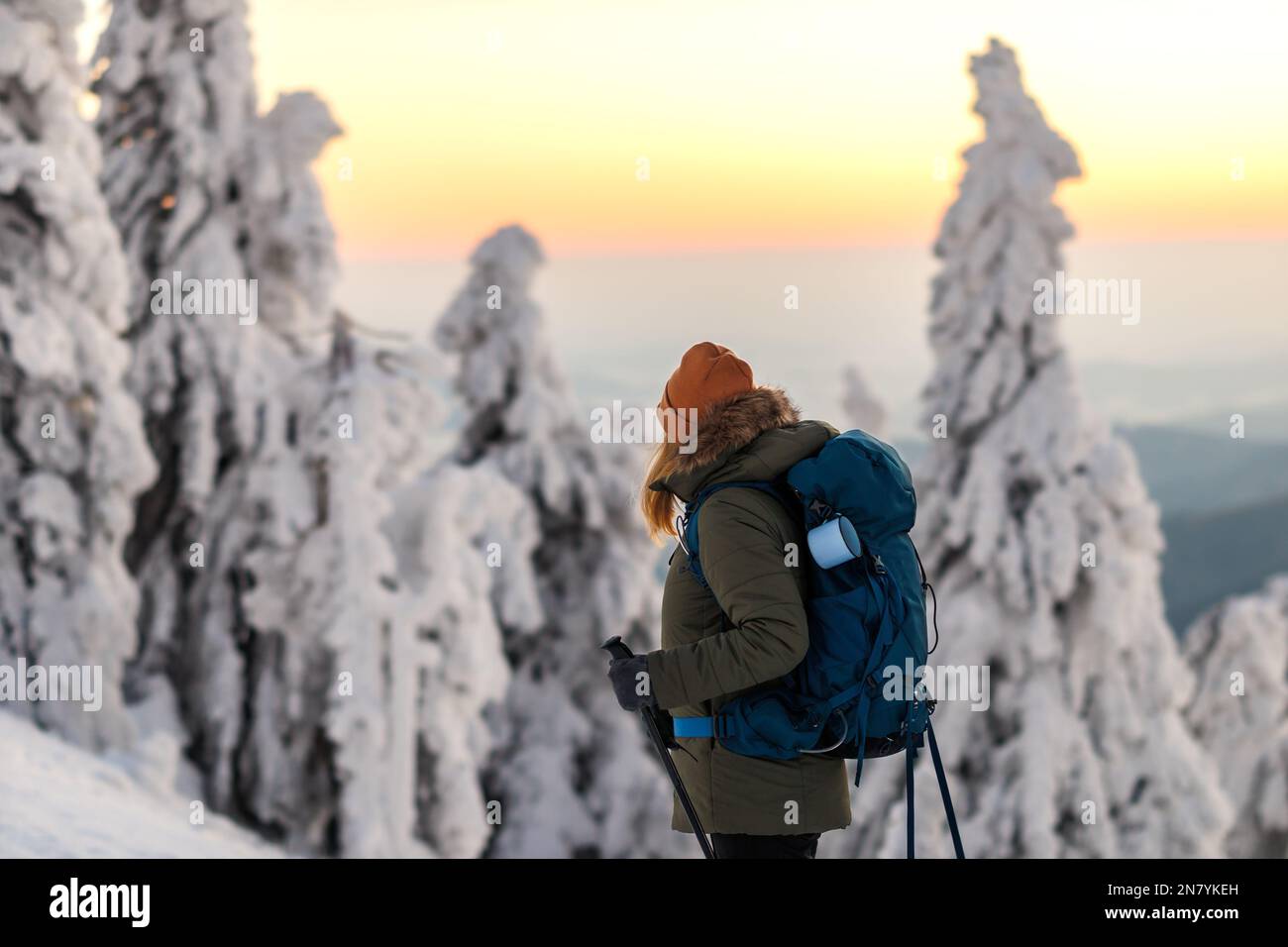 Randonnée en hiver. Femme avec sac à dos trekking dans la forêt de montagne pendant le coucher du soleil. Plaisir de l'aventure dans la nature Banque D'Images