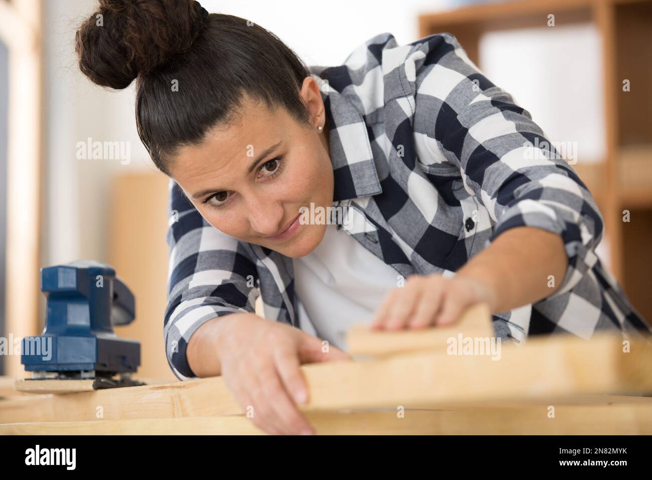 femme sable avec du papier de verre fin une table en bois à l'intérieur Banque D'Images