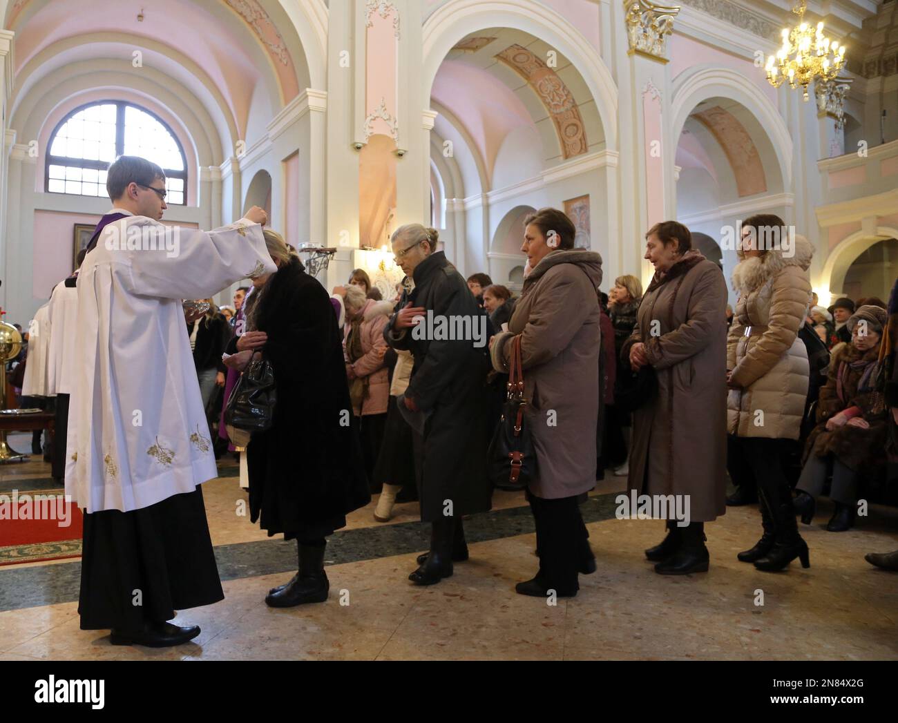 A Belarusian Catholic priest sprinkles ashes on the head of the faithful in the observance of Ash Wednesday, the official start of the Catholic Church's solemn Lenten season, in Cathedral Catholic Church in Minsk, Belarus, Wednesday, Feb. 13, 2013. (AP Photo/Sergei Grits) Banque D'Images