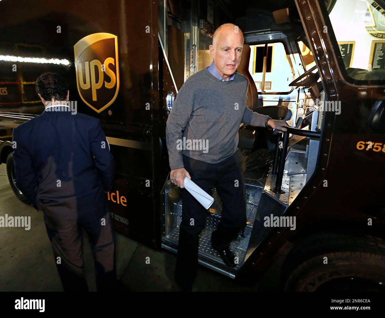 Gov. Jerry Brown steps out of the cab an electric-powered UPS delivery truck at the UPS distribution center in West Sacramento, Calif., Tuesday, Feb. 5, 2013. Brown appeared at the facility to mark the deployment of 100 of the company's zero-emission, electric delivery vehicle fleet.(AP Photo/Rich Pedroncelli) Banque D'Images