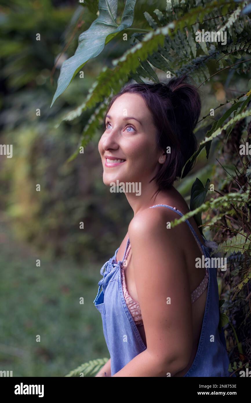 Une photo verticale d'une belle femme du Caucase heureuse, souriant et regardant vers le haut dans un jardin Banque D'Images