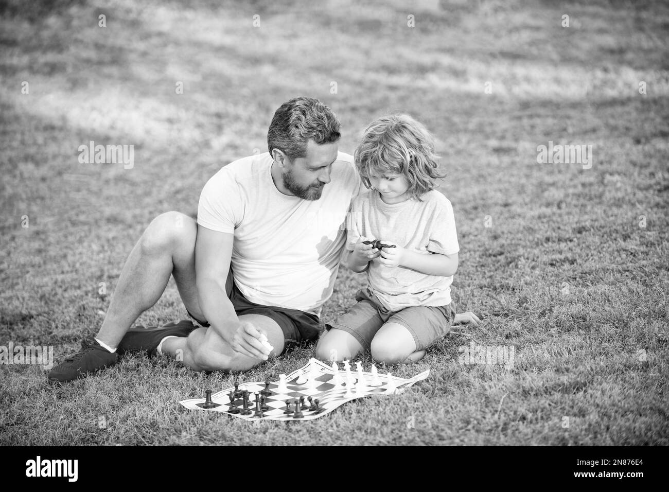 bonne famille de papa et fils enfant jouant aux échecs sur l'herbe verte dans le parc extérieur, décision Banque D'Images