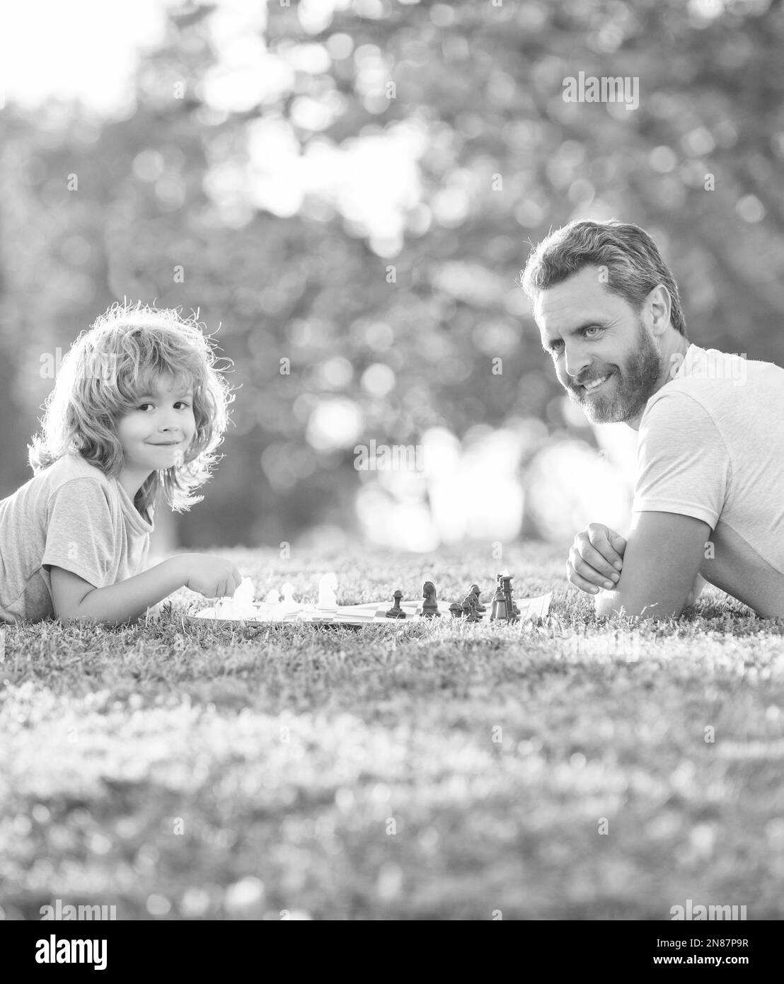 famille heureuse de père homme et son enfant jouant aux échecs sur l'herbe verte dans le parc extérieur, chef-d'œuvre Banque D'Images