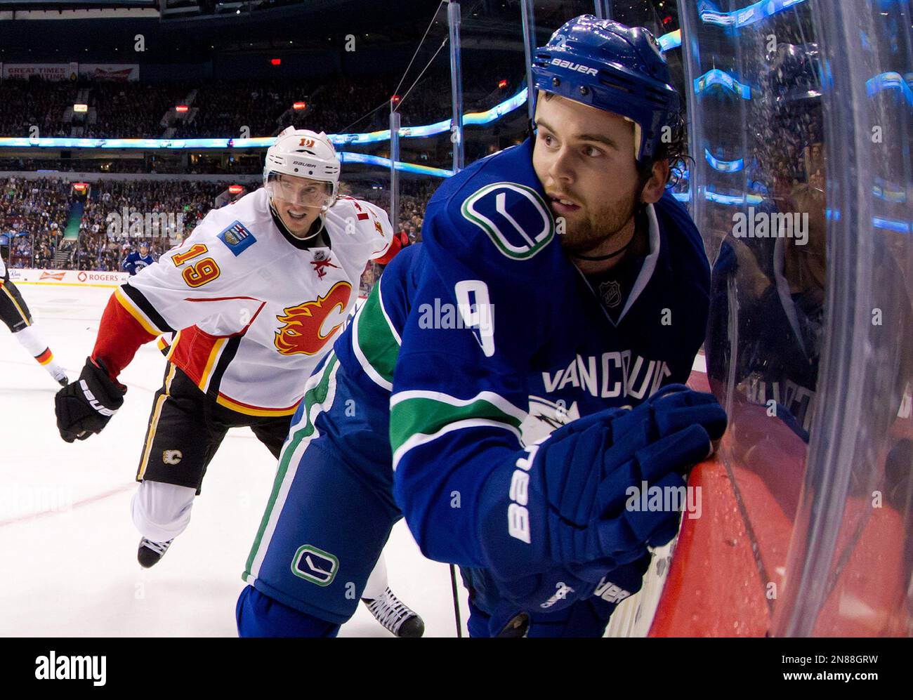 Vancouver Canucks' Zack Kassian, right, is checked into the boards by Calgary Flames' Blair Jones during the first period of an NHL hockey game in Vancouver, B.C., on Wednesday January 23, 2013. THE CANADIAN PRESS/Darryl Dyck Banque D'Images