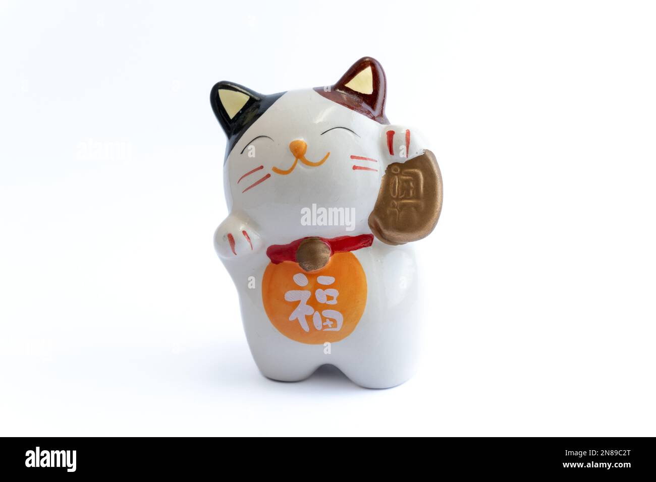 Un Maneki-neko ou aussi connu comme chat de fortune en porcelaine. Symbolisant la chance et la richesse, sur un fond blanc isolé. Banque D'Images