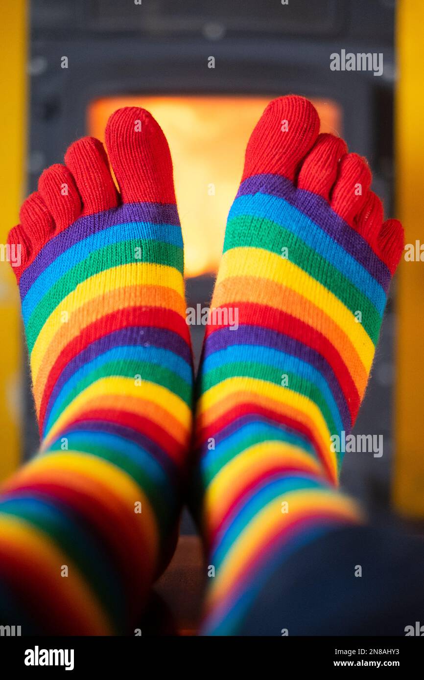 réchauffez vos pieds tout en portant des chaussettes strippy colorées avec un brûleur en bois illuminé en arrière-plan Banque D'Images