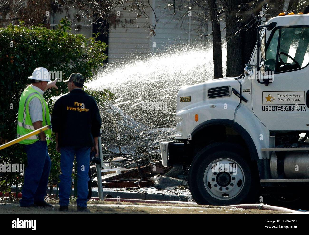 A unidentified worker and a fire investigator stand in front of the remains of an exploded structure as firefighters continue to spray water on the remains Friday, Jan. 11, 2013, in Lewisville, Texas. An explosion Friday in a North Texas neighborhood leveled a home that is part of a local nonprofit's affordable housing program, injuring at least three men and scattering debris.(AP Photo/Tony Gutierrez) Banque D'Images