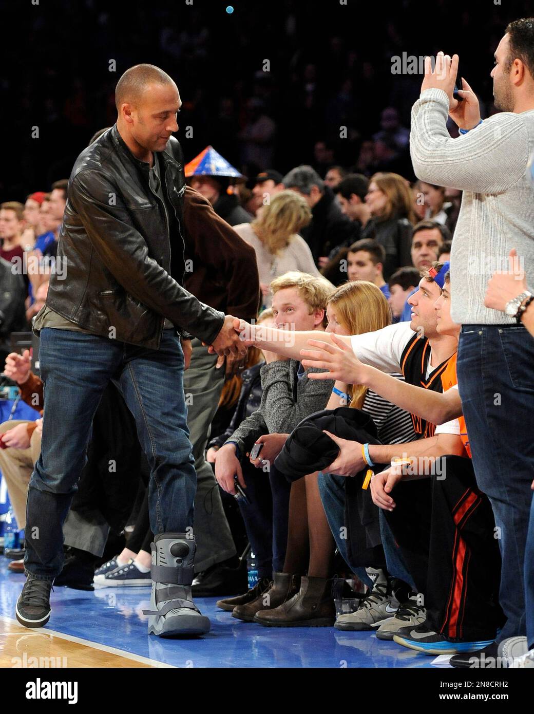 New York Yankee Derek Jeter wearing a boot on his left foot shakes hands with fans as he leaves at the end of the New York Knicks versus Minnesota Timberwolves NBA basketball game on Sunday, Dec. 23, 2012, at Madison Square Garden in New York. (AP Photo/Kathy Kmonicek) Banque D'Images