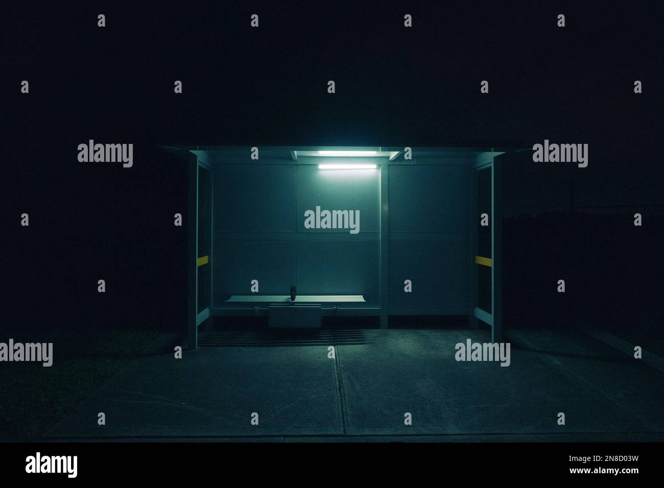 Une image cinématographique d'un arrêt de bus vide la nuit avec une lumière allumée Banque D'Images