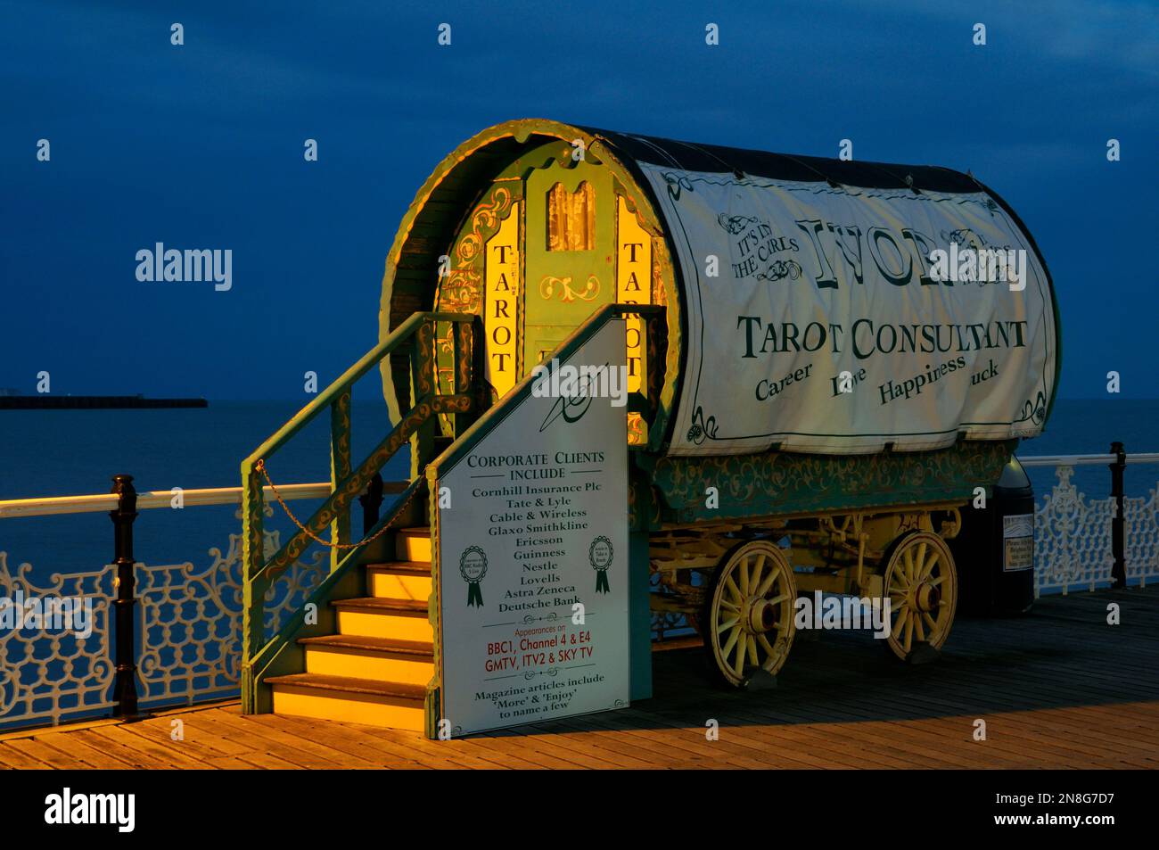 Le lecteur de Tarot Romany Caravan ou chariot tzigane éclairé par des lampadaires au crépuscule sur la promenade de Brighton Palace Pier, East Sussex, Angleterre, Royaume-Uni Banque D'Images