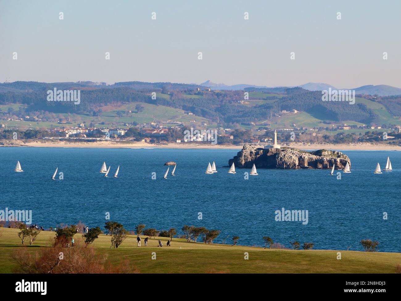 Vue sur le paysage sur le parcours de golf de Matalinas avec une compétition de voile en cours et sur l'île de Mouro et le phare Santander Cantabria Espagne Banque D'Images