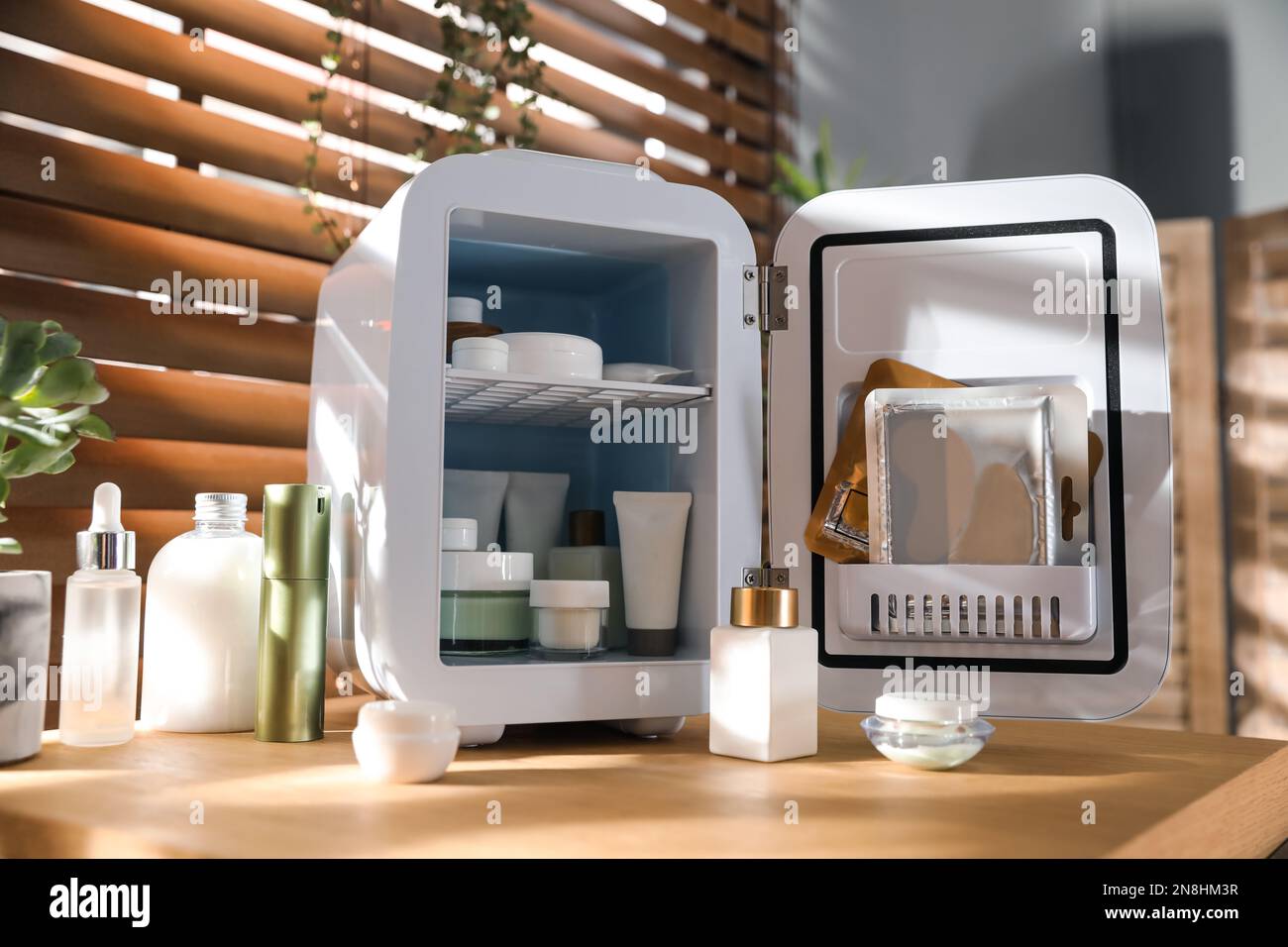 Mini-réfrigérateur avec produits cosmétiques sur une table de coiffeuse en bois Banque D'Images