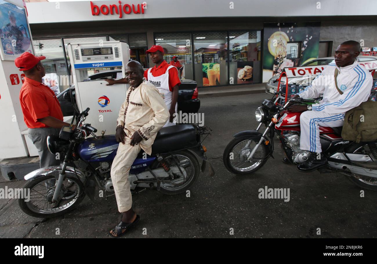 A petrol attendant sells fuel to motorcycle taxis at a Total petrol station in Lagos, Nigeria, Monday, Nov. 19, 2012. French oil company Total SA said Monday it had sold its stake in an offshore oil field near Nigeria for $2.5 billion to the Chinese state-run firm Sinopec Corp., a sign of the China's growing stakes in the West African nation's oil production. (AP Photo/Sunday Alamba) Banque D'Images