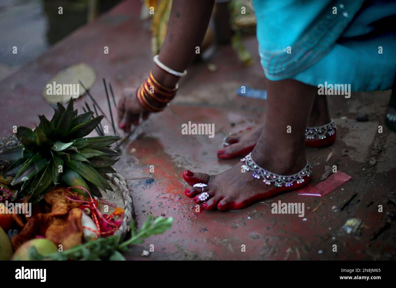 An Indian Hindu woman places incense sticks on the floor on the occasion of Chhat Puja festival in New Delhi, India, Monday, Nov. 19, 2012. Chhath, an ancient Hindu festival, rituals are performed to thank the Sun God for sustaining life on earth. (AP Photo/Altaf Qadri) Banque D'Images