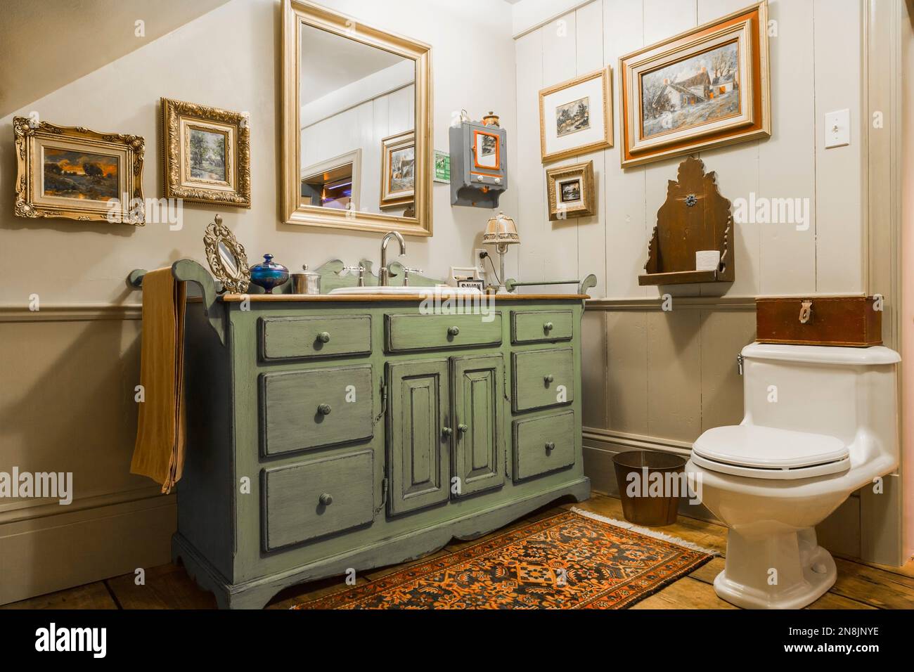 Meuble lavabo en bois antique vert et gris et toilettes en porcelaine blanche dans la salle de bains sur le sol upsatirs à l'intérieur de la vieille maison de chalet Canadiana circa 1805. Banque D'Images