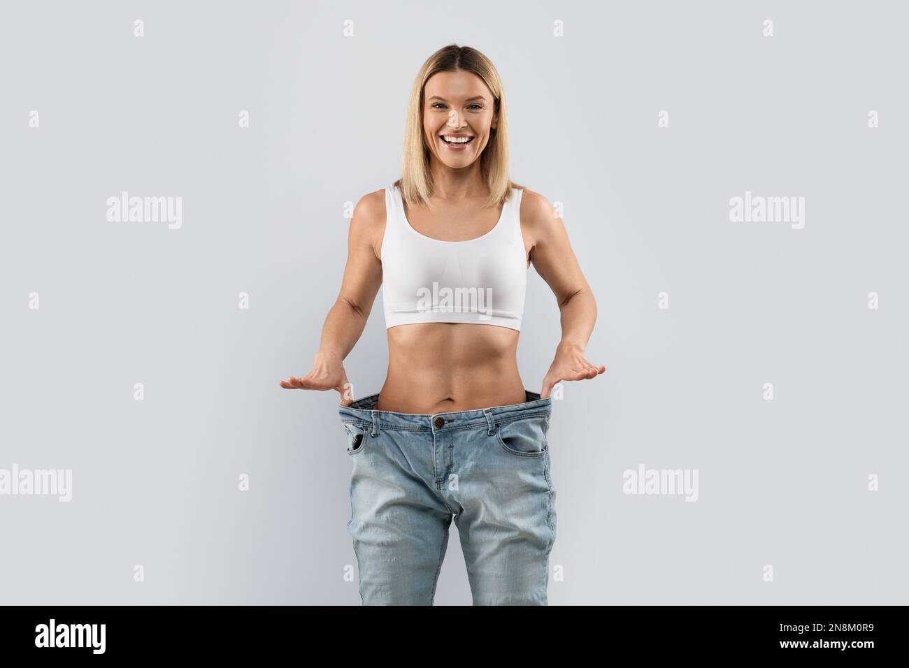 Femme blonde gaie portant un pantalon et souriant Banque D'Images
