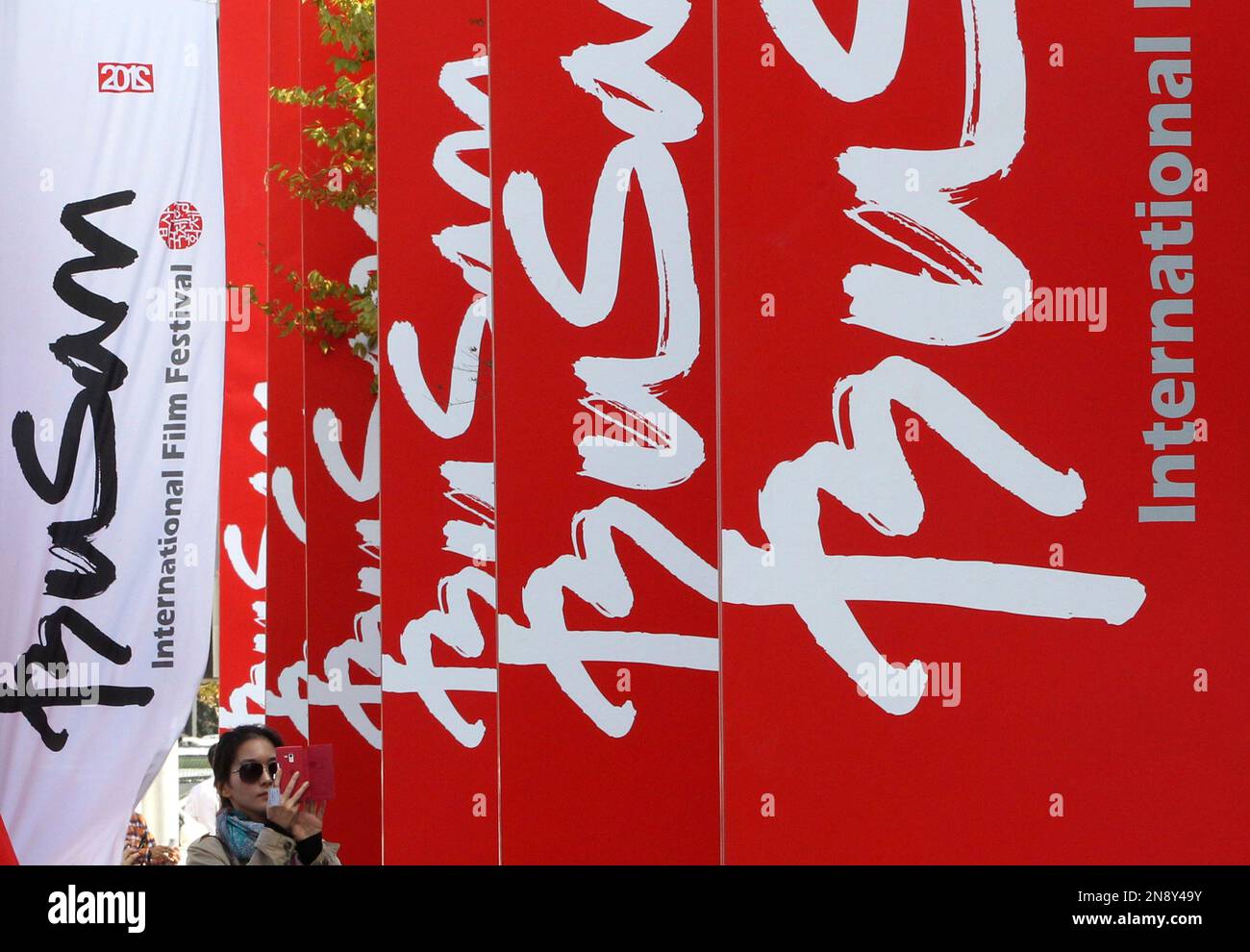 A woman takes pictures of banners advertising the Busan International Film Festival at Busan Cinema Center in Busan, South Korea, Wednesday, Oct. 3, 2012. Along with the now inevitable galaxy of stars promoting blockbusters from across Asia, this year's Busan International Film Festival will screen a North Korean film for the first time in almost a decade as well as six classic Afghan movies that were hidden in a wall to save them from the Taliban. (AP Photo/Ahn Young-joon) Banque D'Images