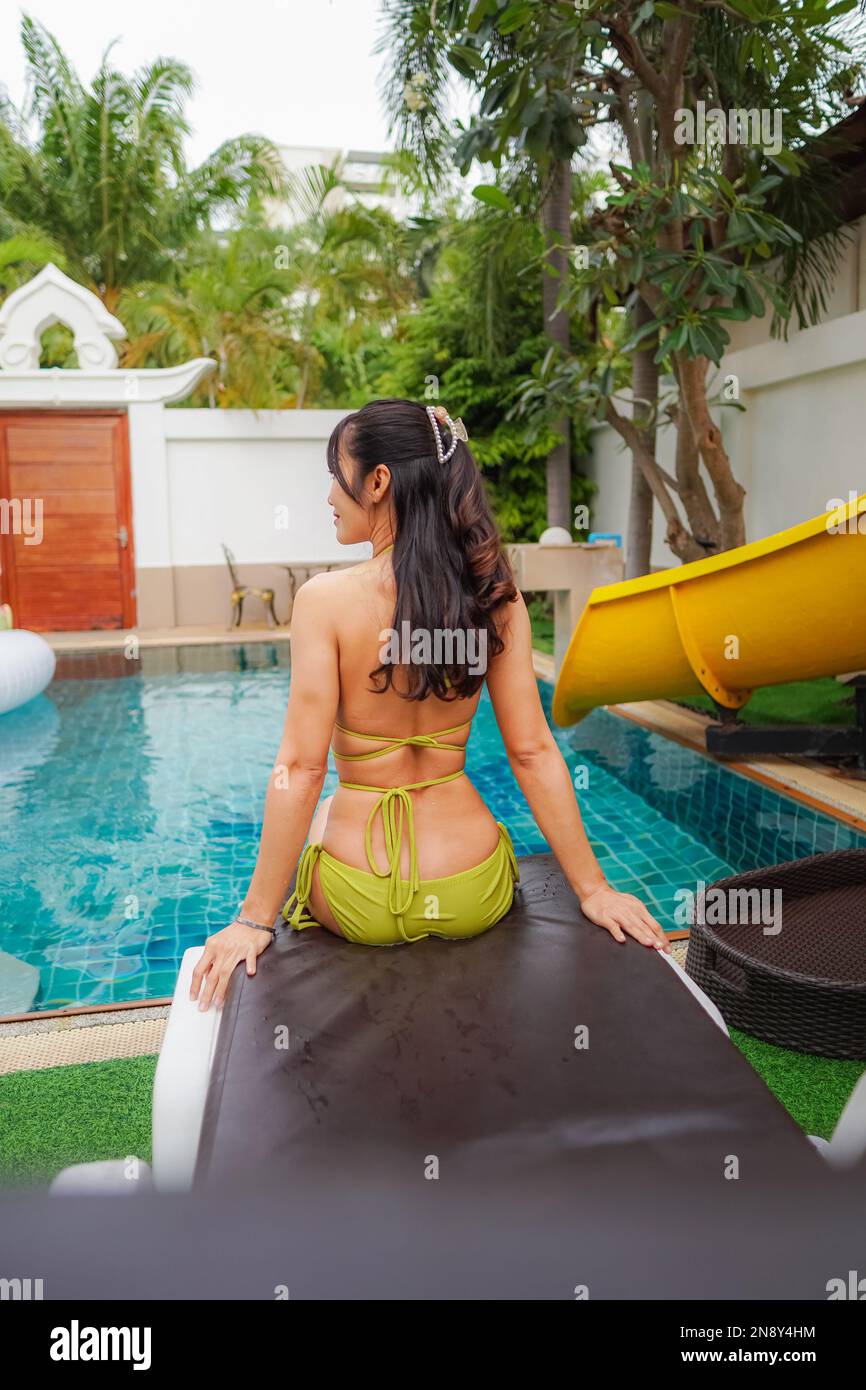 Asiatique jeune femme sexy portant un bikini jaune jouant dans la piscine à Pool Villa Banque D'Images