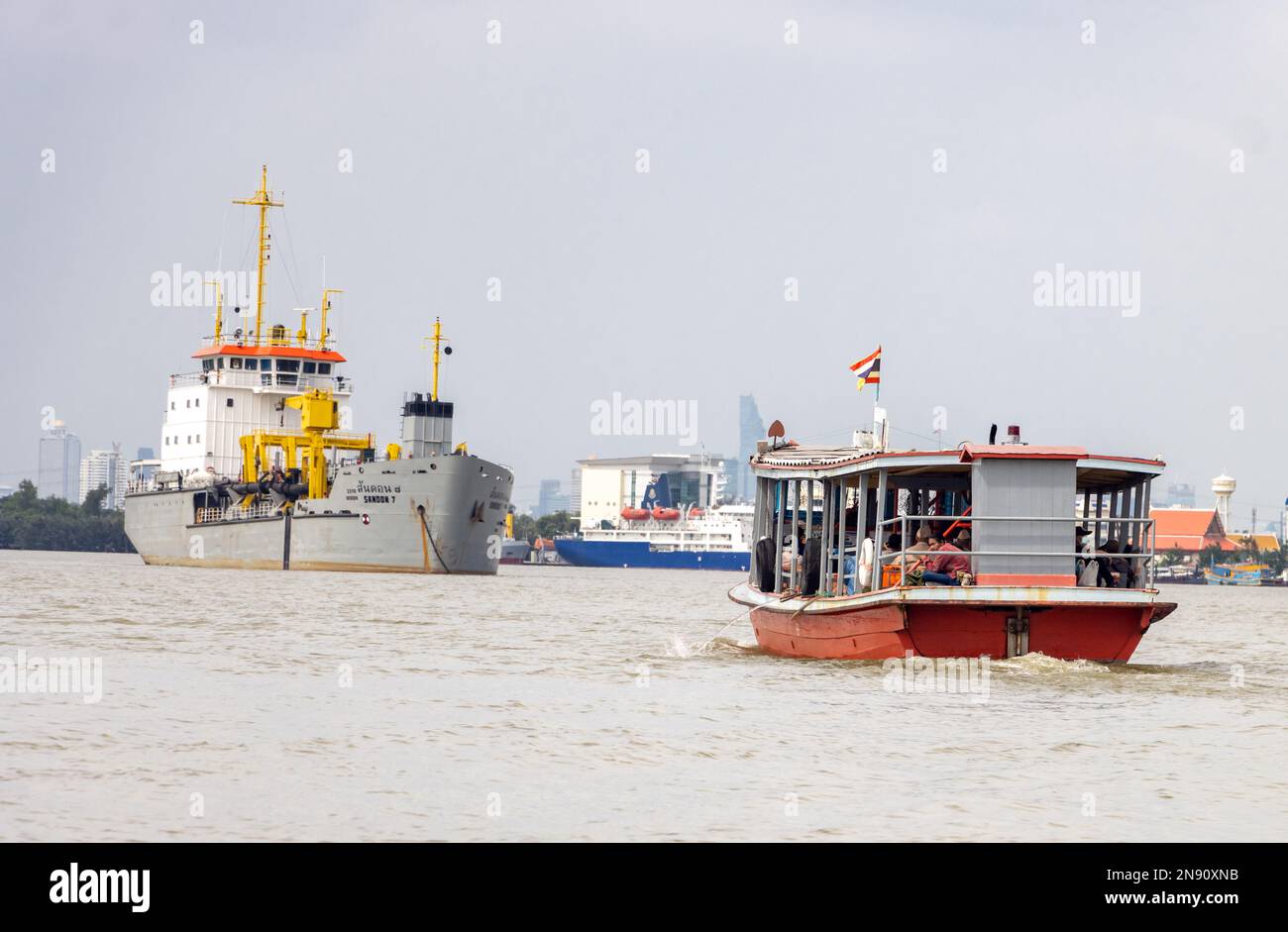 SAMUT PRAKAN, THAÏLANDE, NOVEMBRE 13 2022, le ferry transporte des passagers sur la rivière Chao Phraya, sur un fond ancré trémie aspirante traînante Banque D'Images