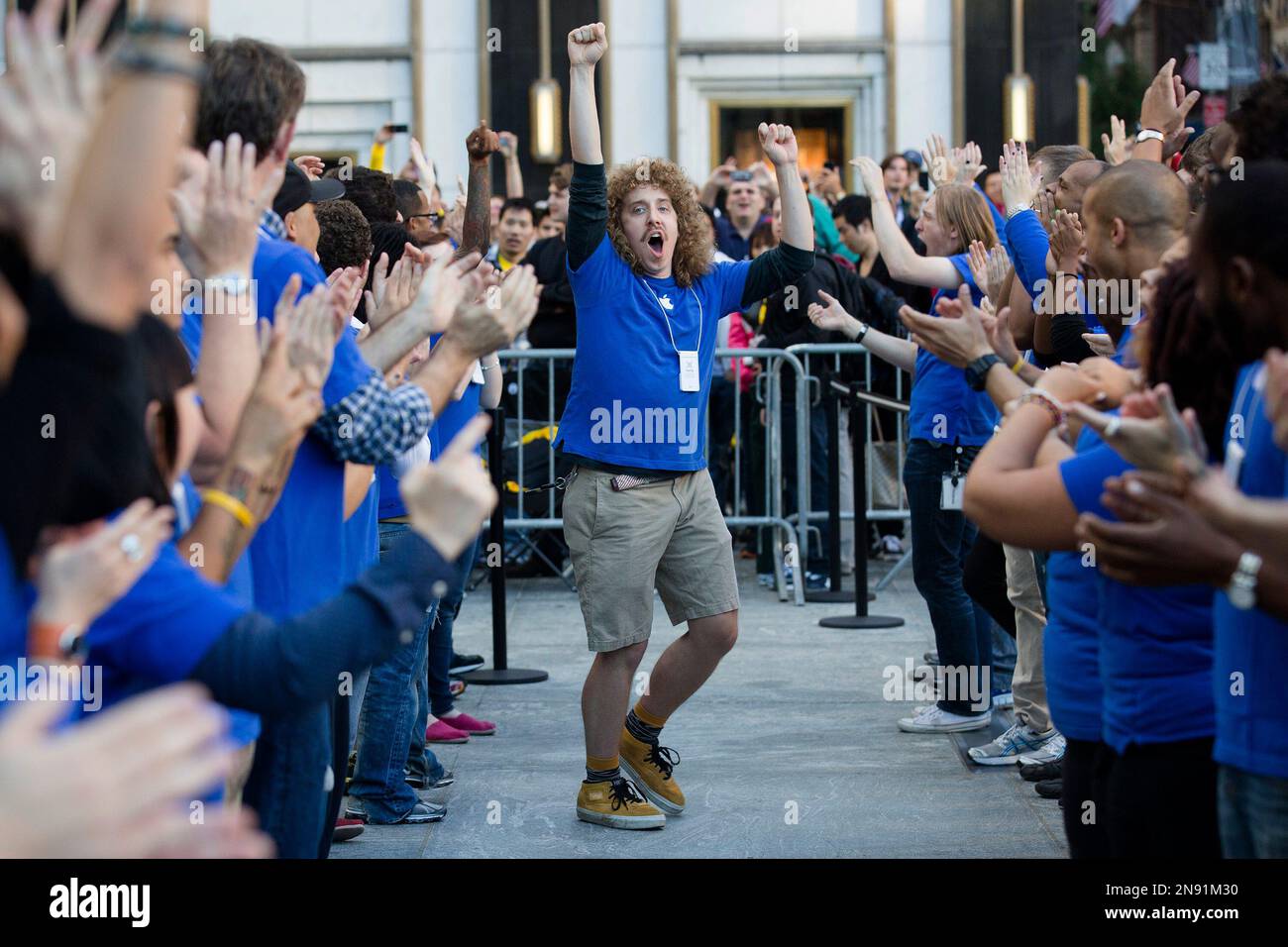 An Apple employee riles up his coworkers outside the Fifth Avenue Apple store to celebrate the release of the iPhone 5, Friday, Sept. 21, 2012, in New York. Hundreds of people waited in line through the early morning to be among the first to get their hands on the highly anticipated phone. (AP Photo/John Minchillo) Banque D'Images
