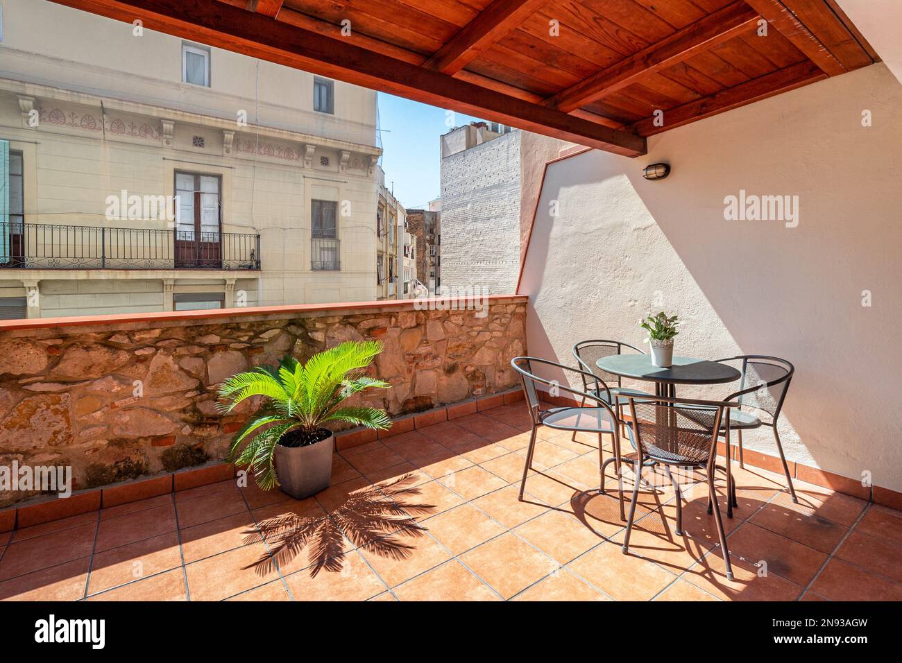 Grande terrasse avec un toit en bois donnant sur la ville avec un ciel bleu. Sur la terrasse inondée de lumière du soleil au milieu il y a un Banque D'Images