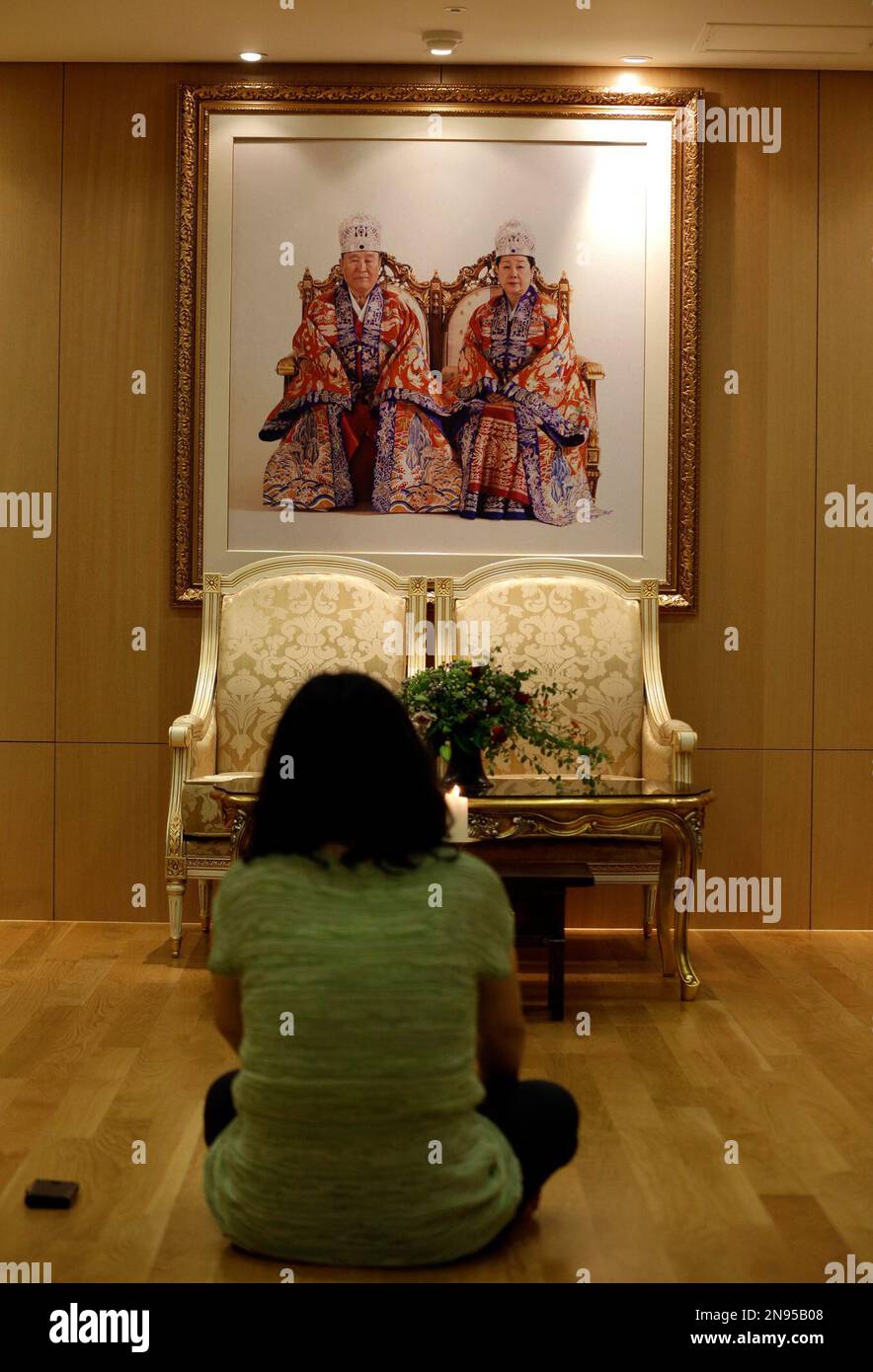 A woman looks at the portraits of the Rev. Sun Myung Moon, left, and wife Han Hak-ja at a Unification church in Seoul, South Korea, Monday, Sept. 3, 2012. Moon, the self-proclaimed messiah who founded the church, died Monday, Sept. 3, 2012, at a church-owned hospital near his home in Gapyeong County, northeast of Seoul, church officials said. He was 92. (AP Photo/Lee Jin-man) Banque D'Images