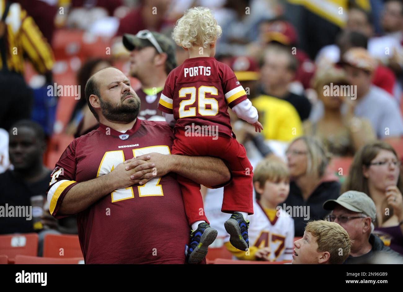 A Washington Redskins fan holds up a child in the stands during a preseason NFL football game against the Indianapolis Colts, Saturday, Aug. 25, 2012, in Landover, Md. (AP Photo/Nick Wass) Banque D'Images