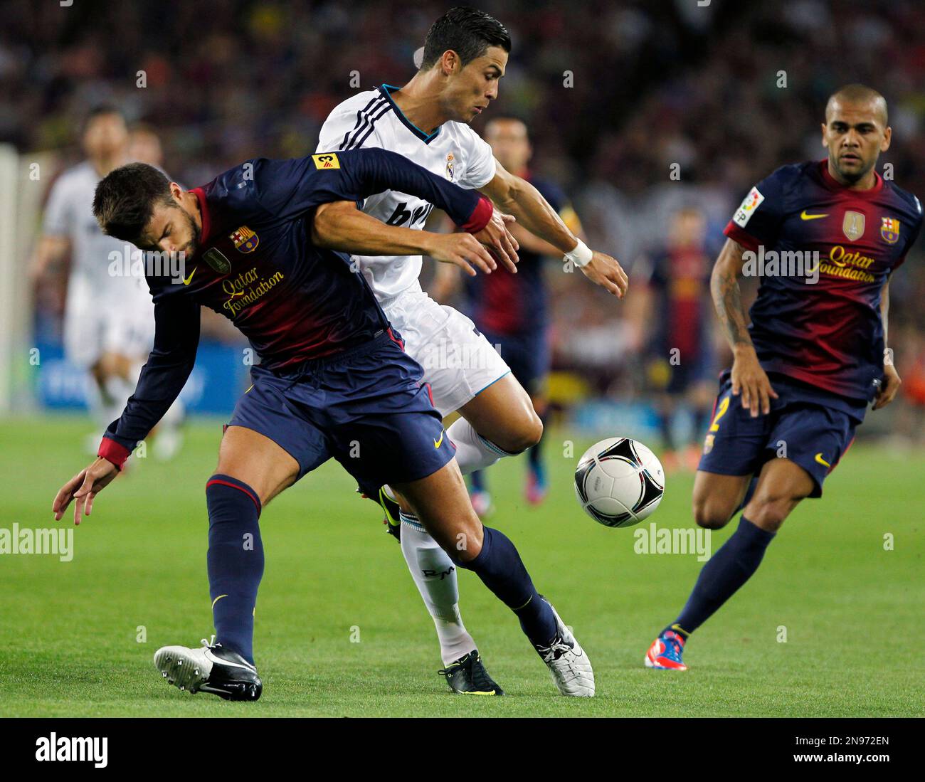 FC Barcelona's Gerard Pique, left, vies for the ball with Real Madrid's Cristiano Ronaldo, centre, from Portugal, during a Spanish Supercup first leg soccer match at the Camp Nou stadium in Barcelona, Spain, Thursday, Aug. 23, 2012. (AP Photo/Andres Kudacki) Banque D'Images