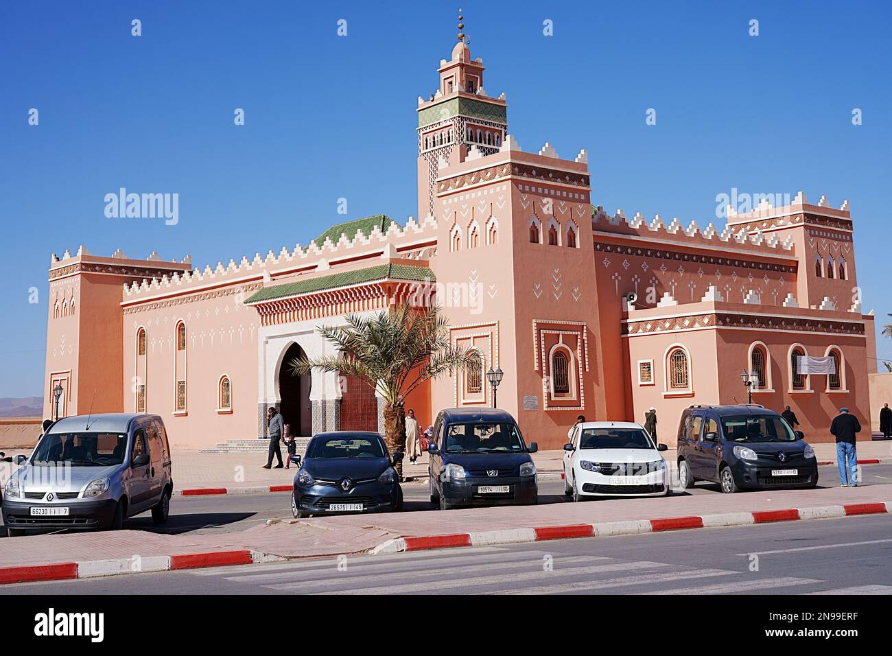 Voitures devant la mosquée dans la ville africaine de Zagora dans la région de Draa Tafilalet au Maroc, ciel bleu clair en 2023 chaude et ensoleillée jour d'hiver le janvier. Banque D'Images