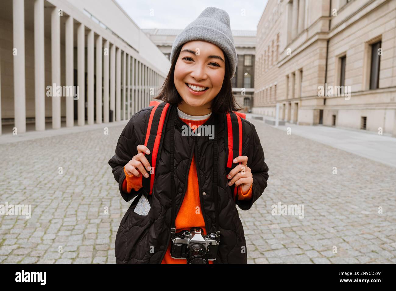 Jeune femme asiatique souriante touriste dans des vêtements chauds marchant dans la vieille rue de la ville Banque D'Images