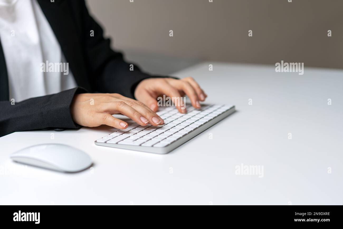 Les femmes se font une main sur le clavier blanc de l'ordinateur pour photographier en gros plan avec l'espace de copie. Saisie de modèle sur le clavier. Banque D'Images