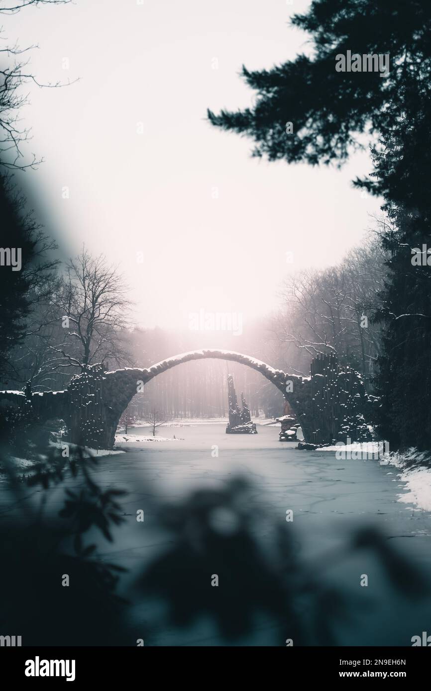 Milieu de la Terre en hiver : un vieux pont en pierre au-dessus d'un lac gelé Banque D'Images