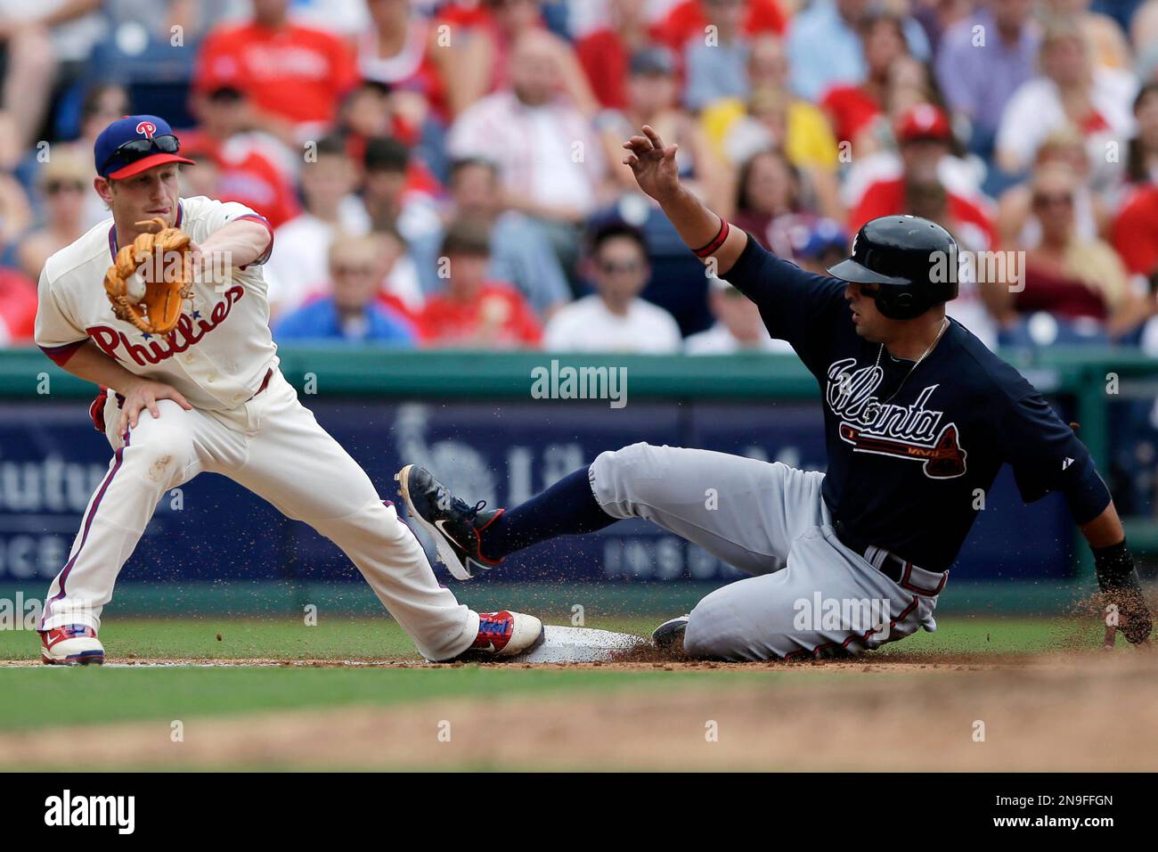 Atlanta Braves' Martin Prado, right, slides into third base as Philadelphia Phillies third baseman Mike Fontenot handles the throw on a single by Jason Heyward in the fifth inning of a baseball game, Sunday, July 8, 2012, in Philadelphia. Atlanta won 4-3. (AP Photo/Matt Slocum) Banque D'Images