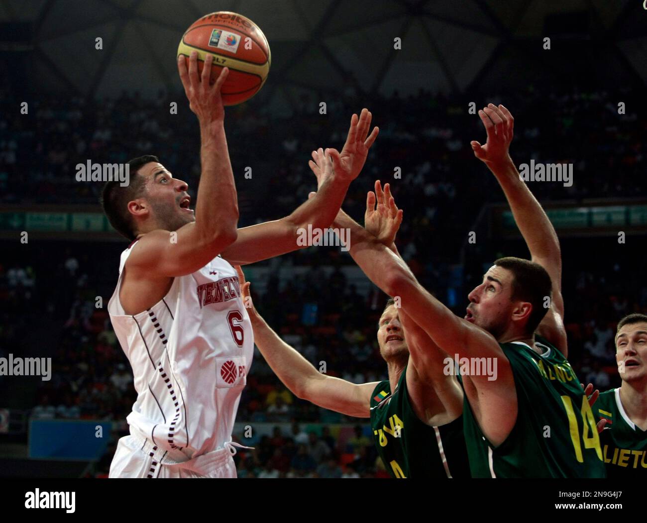 Venezuela's Greivis Vasquez, left, shoots over Lithuania's Rimantas Kaukenas, center, and Jonas Valanciunas during an Olympic qualifier basketball game in Caracas, Venezuela, Tuesday, July 3, 2012. (AP Photo/Juan Carlos Solorzano) Banque D'Images