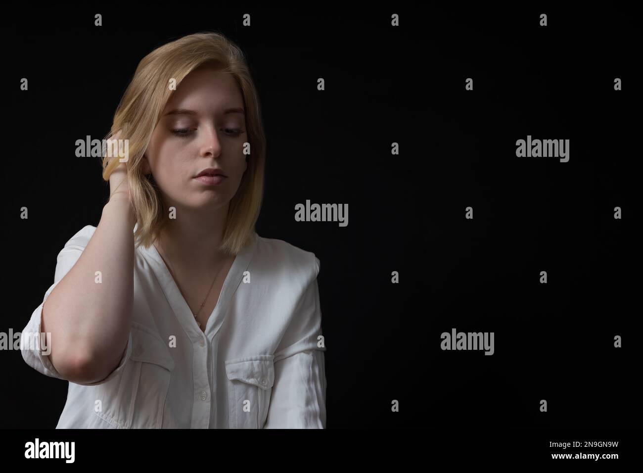 Portrait-clé bas de blonds triste jeune femme a pleurer dans une chemise blanche. Banque D'Images