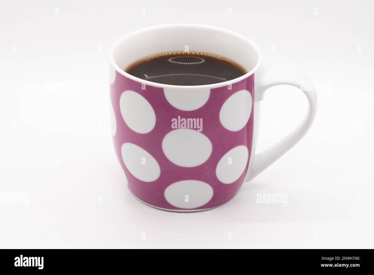 Tasse à café rose avec cercles blancs isolés sur fond blanc Banque D'Images