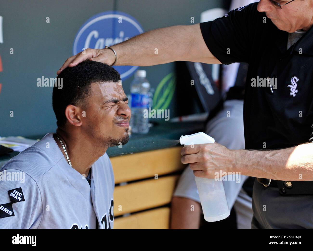 Chicago White Sox' Eduardo Escobar closes his eyes as trainer Herm Schneider sprays him with cool water for relief from oppressive heat and high humidity during a baseball game against the Minnesota Twins Wednesday, June 27, 2012 in Minneapolis. (AP Photo/Jim Mone) Banque D'Images