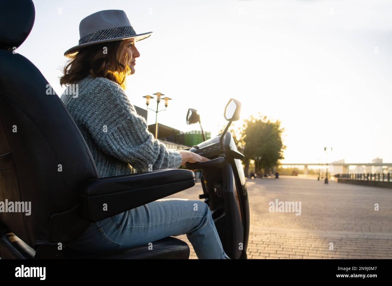 Femme touriste à bord d'un scooter électrique à quatre roues sur une rue de la ville. Banque D'Images