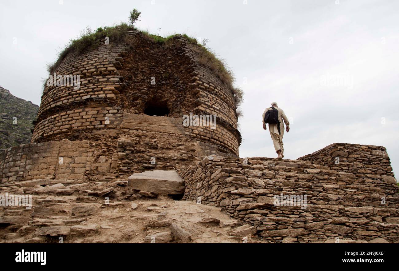 In this May 24, 2012 photo, a villager walks to a Buddhist stupa called the "Amlukdara," which was damaged by thieves looking for statues in Pakistan's Swat Valley. A team funded by the Italian government is working with Pakistan's archaeology department to restore and preserve centuries-old Buddhist sites in northwest Pakistan. Swat was once an important center of Buddhist culture and trade. The monk credited with introducing Buddhism to Tibet, Padmasambhava, was born in Swat. (AP Photo/B.K. Bangash) Banque D'Images