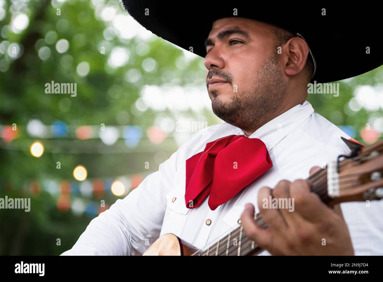 Musicien mexicain mariachi avec guitare sur fond flou de fête Banque D'Images