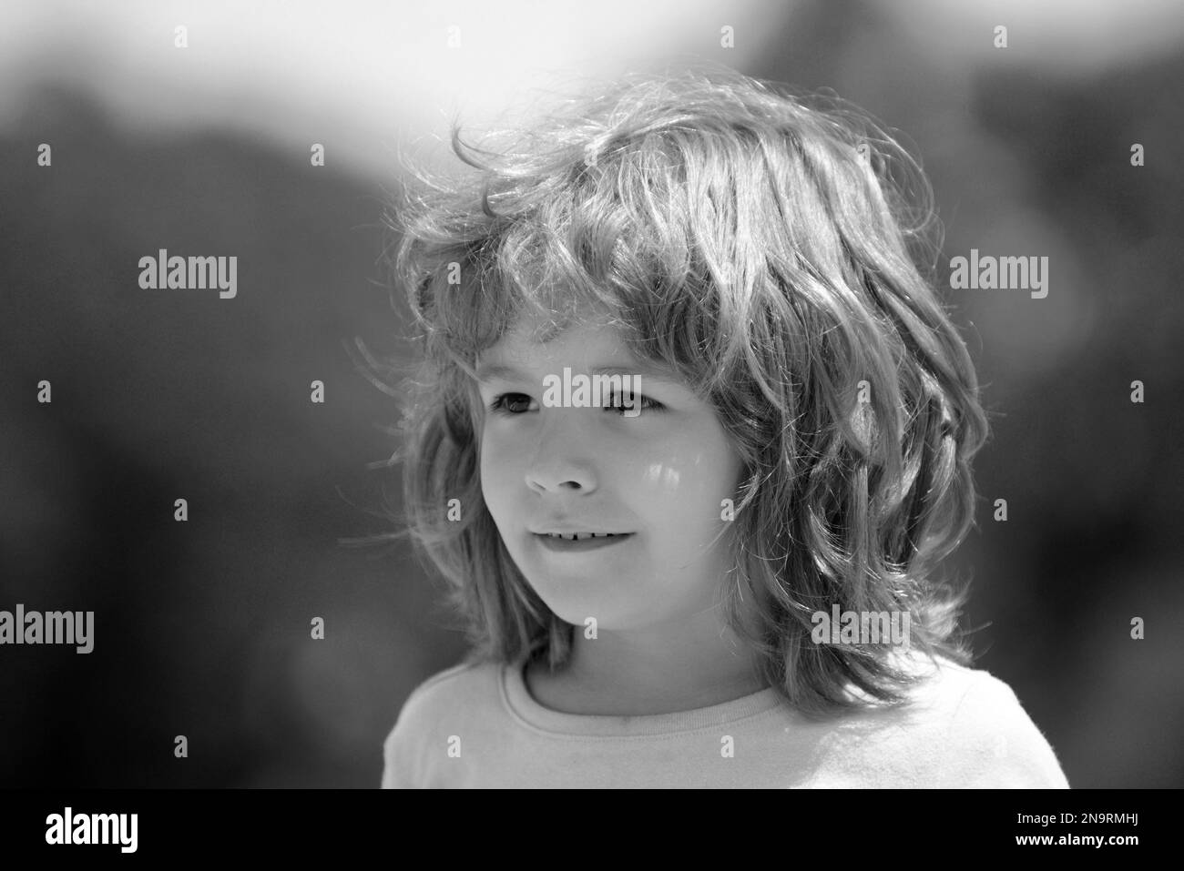 Gros plan pour enfants. Concept des émotions des enfants. Portrait d'un jeune enfant souriant à l'extérieur. Arrière-plan flou. Banque D'Images