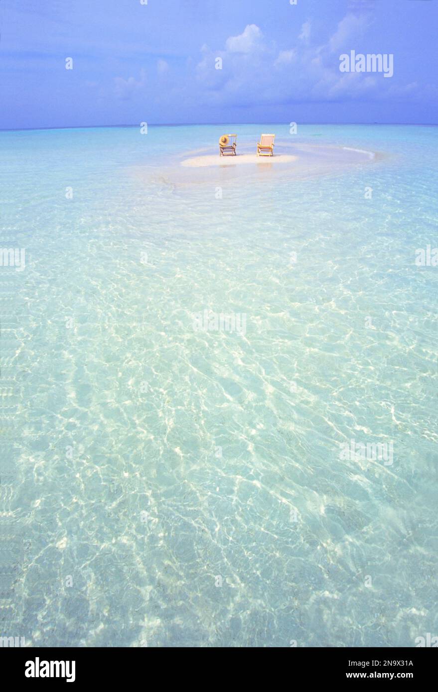 Deux chaises sur un petit bar de sable blanc entouré d'eau turquoise claire de l'océan Banque D'Images