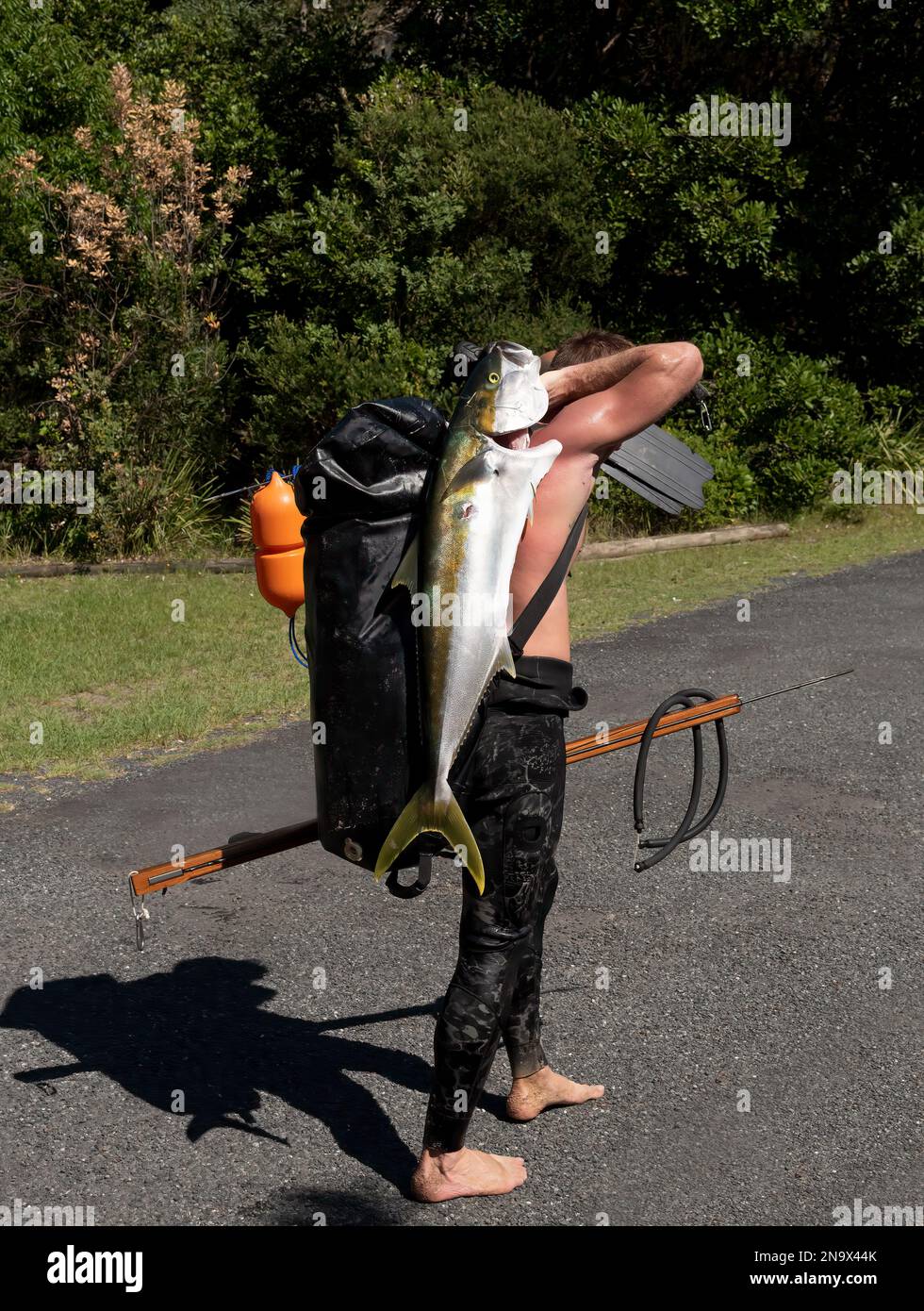 Pêcheur de lance non identifié avec une prise d'un poisson-roi à queue jaune Banque D'Images