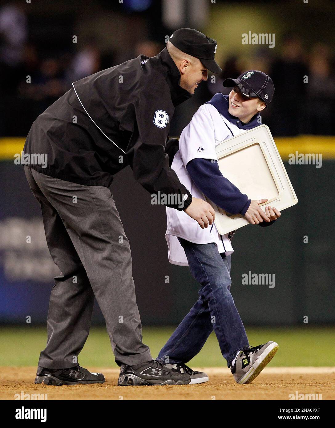 U.S. Army 1st Sgt. Steve Smerer, left, surprises his son Kyle Smerer, 13, by dressing as an umpire and meeting the boy at second base during a base-stealing promotion between innings as the Seattle Mariners play the Oakland Athletics in a baseball game Friday, April 13, 2012, in Seattle. Smerer, a 17-year service member, had just returned from a tour of duty in Afghanistan. Smerer is based at Joint Base Lewis McChord. (AP Photo/Elaine Thompson) Banque D'Images