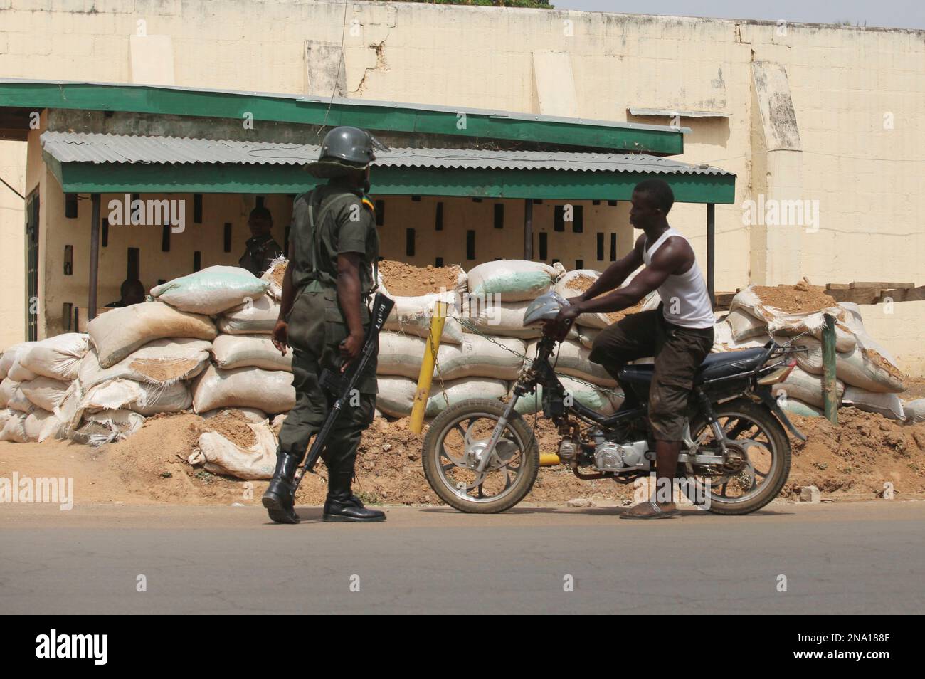An officer stops a motor taxi rider on a street in Kaduna, Nigeria, Tuesday, April 10, 2012. In this Nigerian city where soldiers stop cars at sandbagged checkpoints and police officers carrying assault rifles warily guard their fortified headquarters, a local church could only weld together small barriers made of scrap iron to block the road to their sanctuary.(AP Photos/Sunday Alamba) Banque D'Images