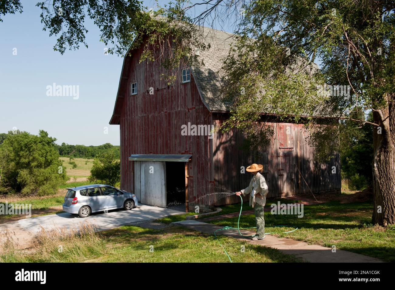 Une femme arrose des graines de graminées dans une ferme ; Dunbar, Nebraska, États-Unis d'Amérique Banque D'Images