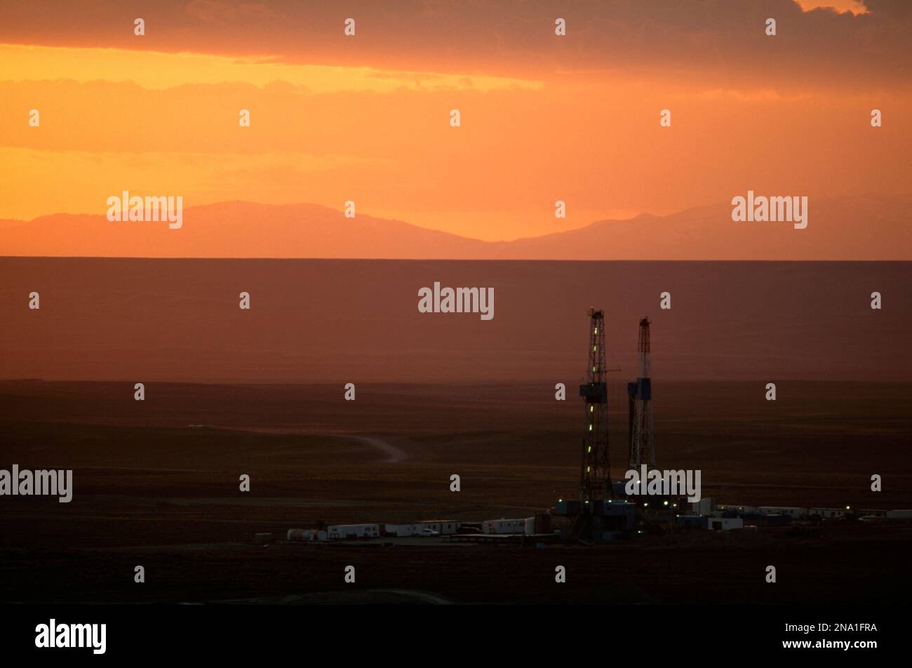 Les plates-formes de forage au gaz naturel parsèment le paysage du Wyoming avec un ciel orangé au coucher du soleil ; Pinedale, Wyoming, États-Unis d'Amérique Banque D'Images