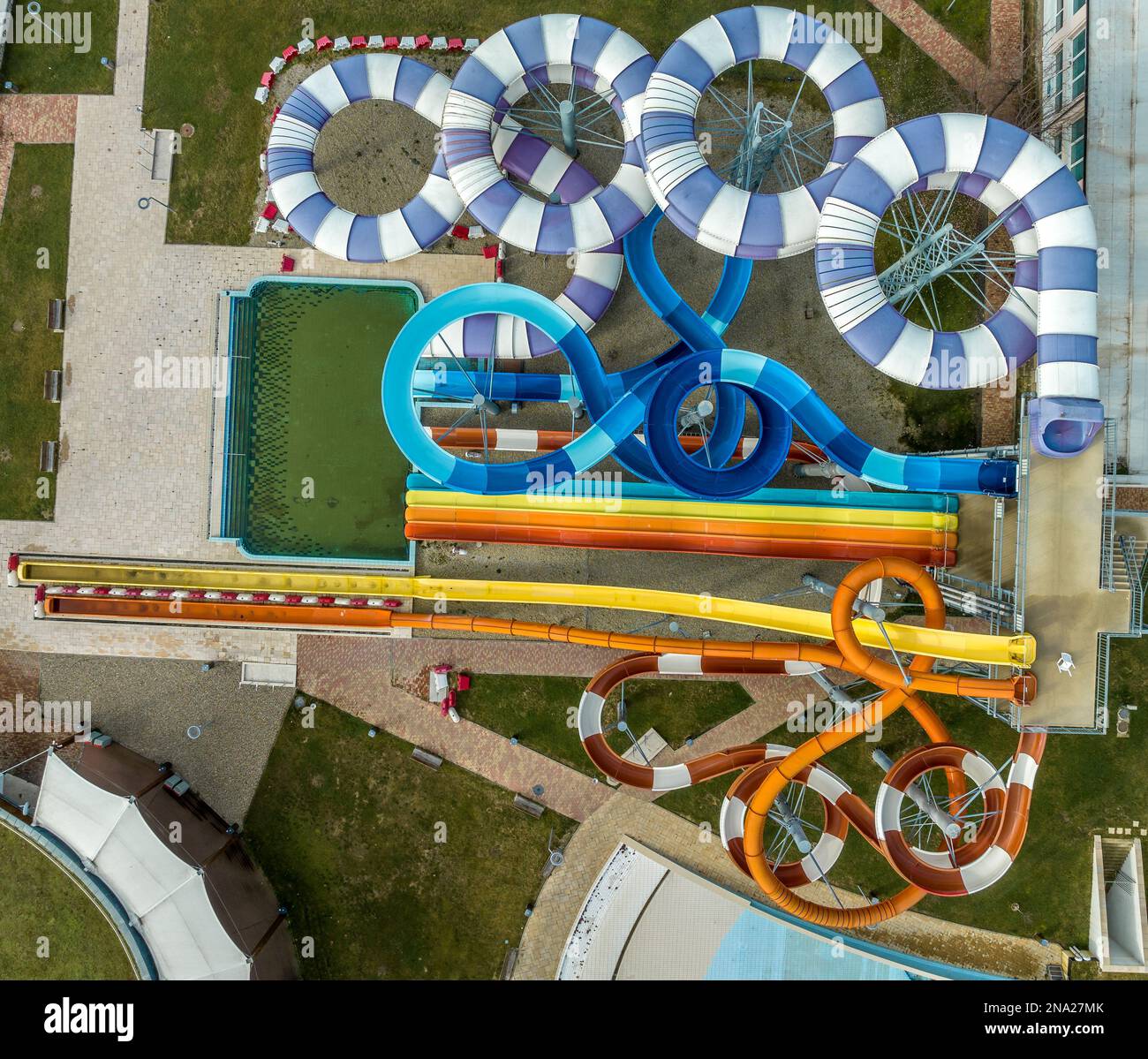 Vue aérienne sur les toboggans aquatiques colorés et amusants d'un parc aquatique extérieur et d'une piscine intérieure en forme de fleur Banque D'Images