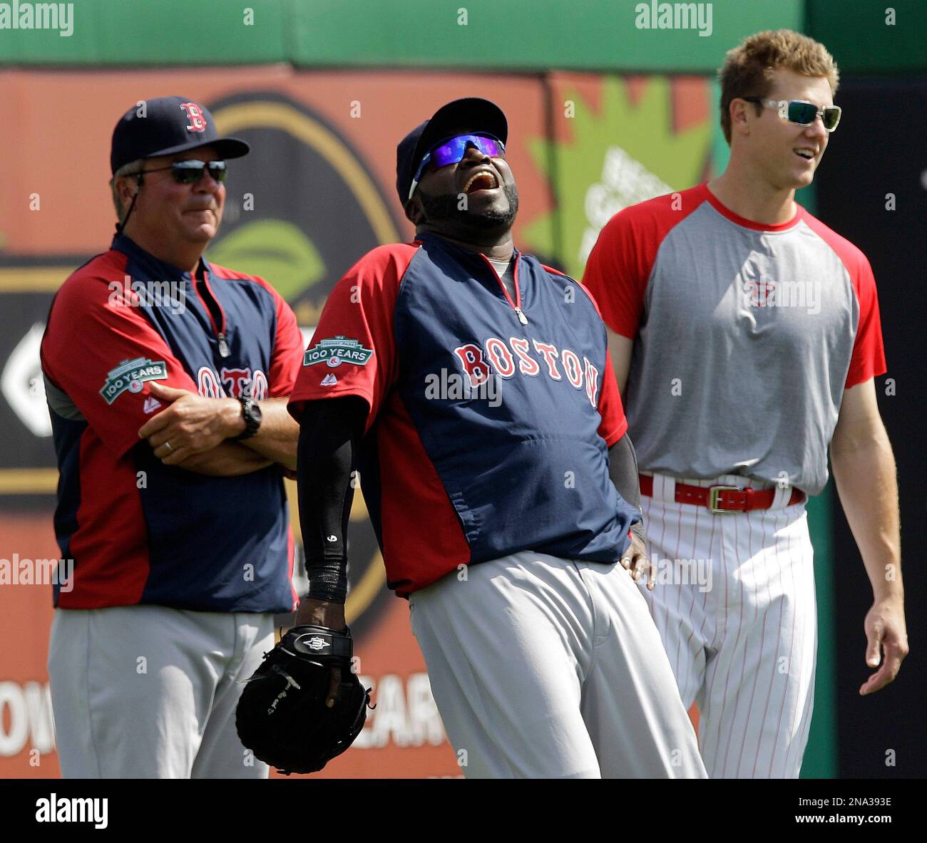 Boston Red Sox bullpen coach Gary Tuck, left, watches as designated hitter David Ortiz, center, laughs heartily with former teammate and current Philadelphia Phillies closer Jonathan Papelbon in the outfield before their spring training baseball game in Clearwater, Fla., Monday, March 26, 2012. (AP Photo/Kathy Willens) Banque D'Images