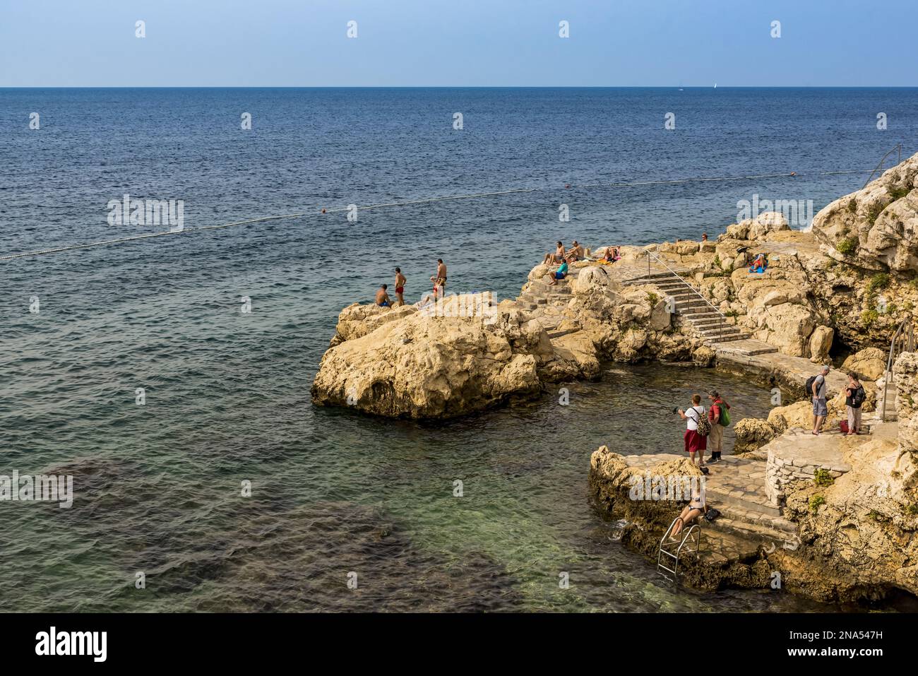 Touristes nageant et bronzant le long de la côte de la mer Adriatique ; Rovinj, Croatie Banque D'Images